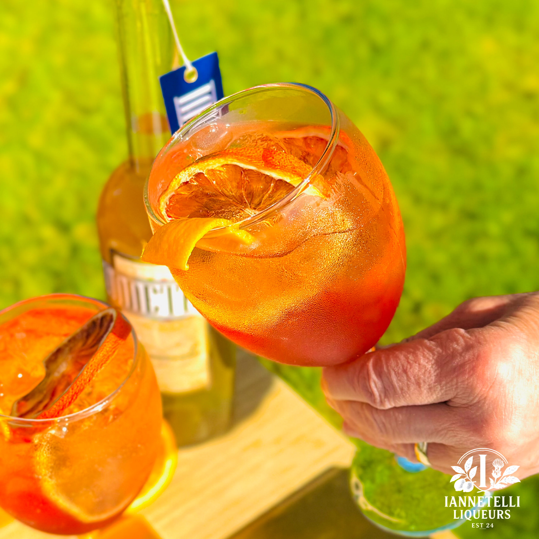 Glass of Arancello spritz with orange garnish being held by hand