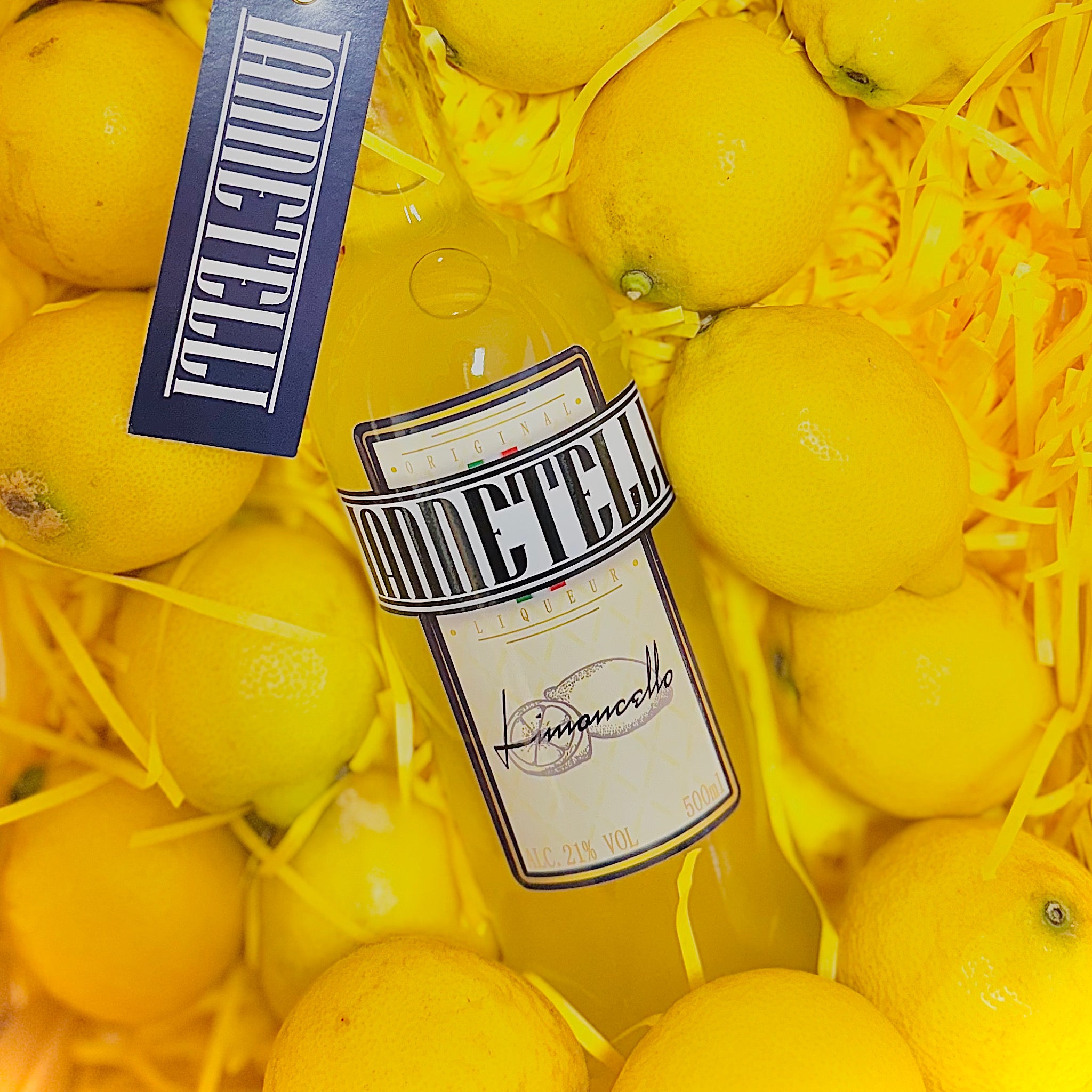 Artisan Iannetelli Limoncello bottle in a wooden crate surrounded by fresh lemons and yellow straw